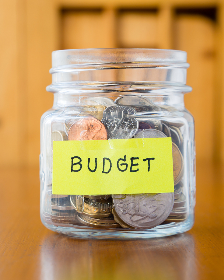 Glasburk märkt 'Budget' fylld med mynt – en påminnelse om vikten av koll på ekonomin med hjälp av Almis budgetmall för företag.
