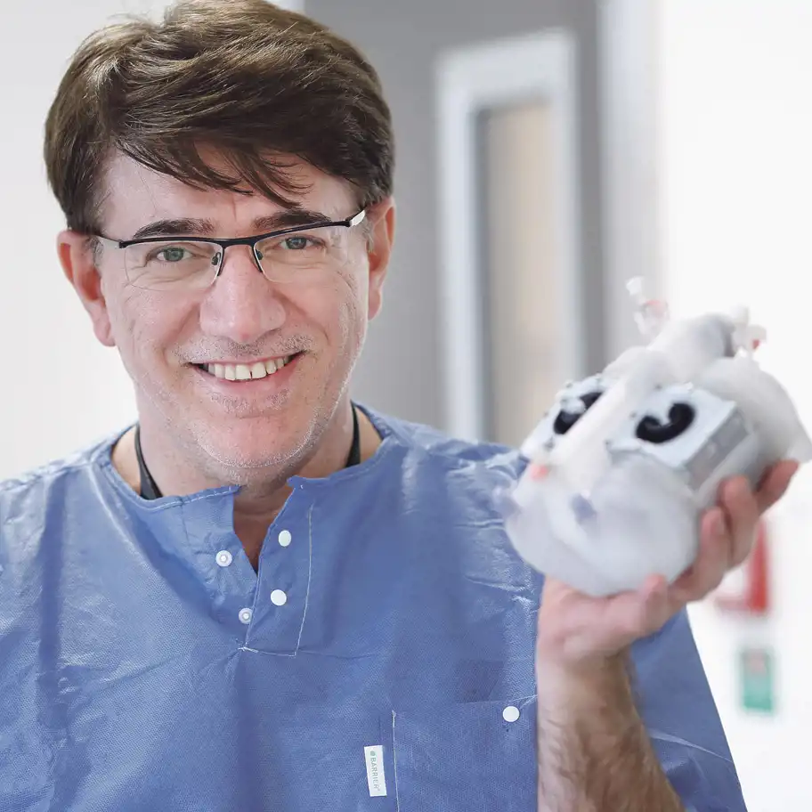 Azad Najar håller artificiellt hjärta i sin hand.