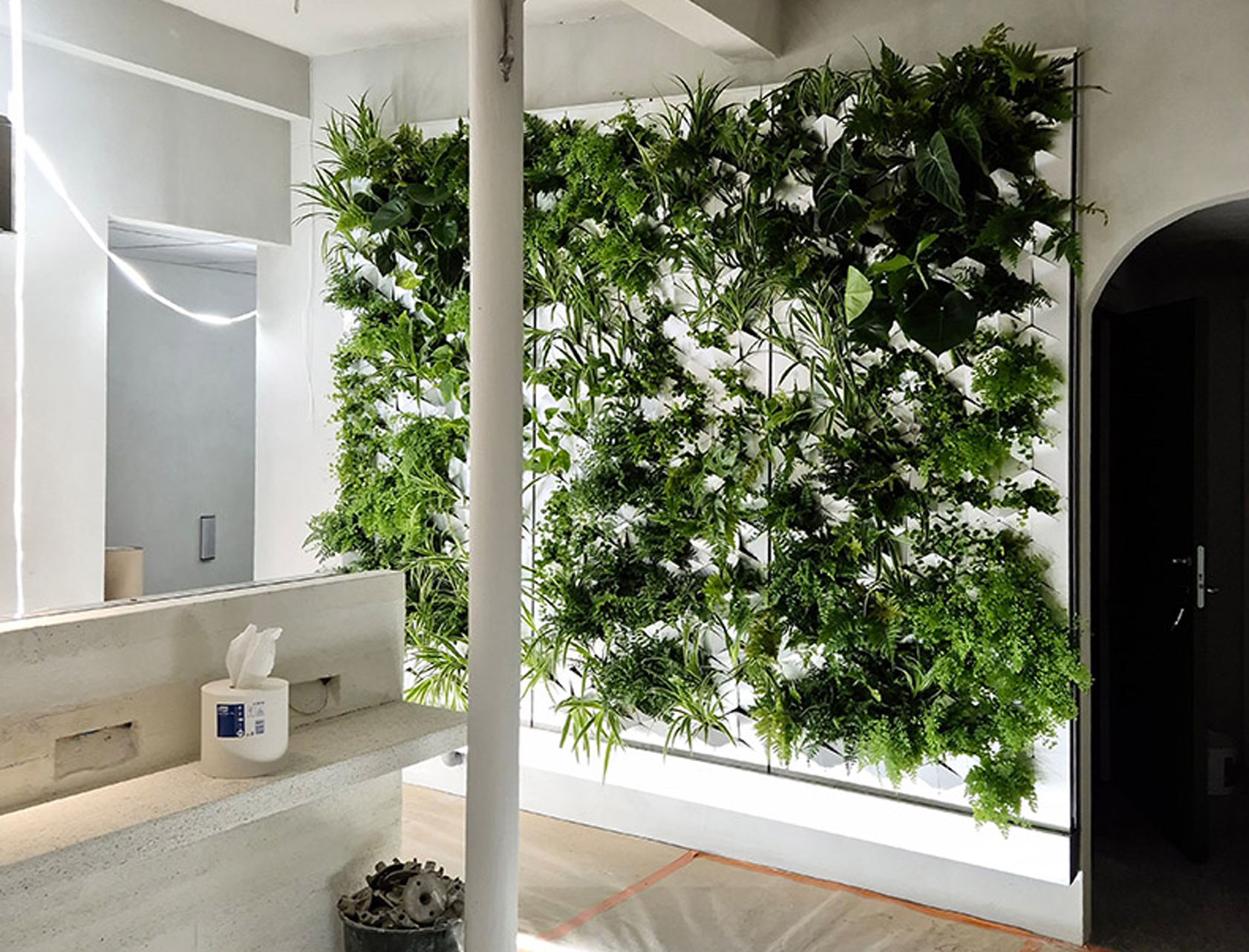 Inomhusmiljö med en stor växtvägg från Butong, där grönska klättrar över en vit panelstruktur i ett ljust rum.