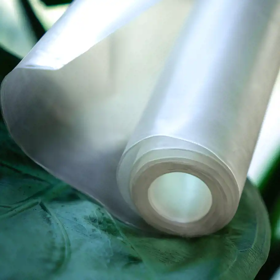 En rulle halvtransparent bioplast placerad på ett grönt blad, med en mjuk och naturlig ljussättning som framhäver materialets struktur.