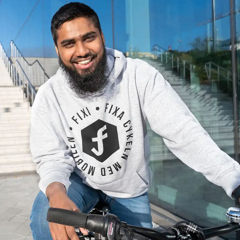 Rafi Mohammad sitter på en cykel och tittar in i kameran och ler. 