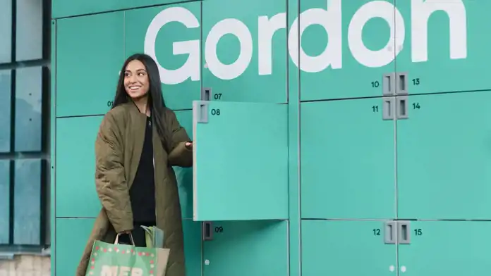 Kvinna som ska hämta ett paket i ett Gordon-utlämningsställe.