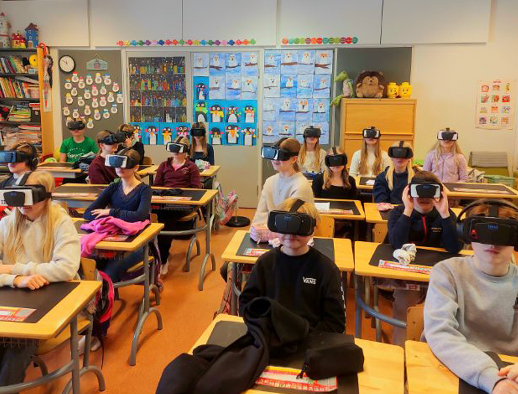 Elever sitter vid sina skolbänkar i ett klassrum och använder VR-glasögon från Imvi Labs för att träna samsyn och läsförmåga.