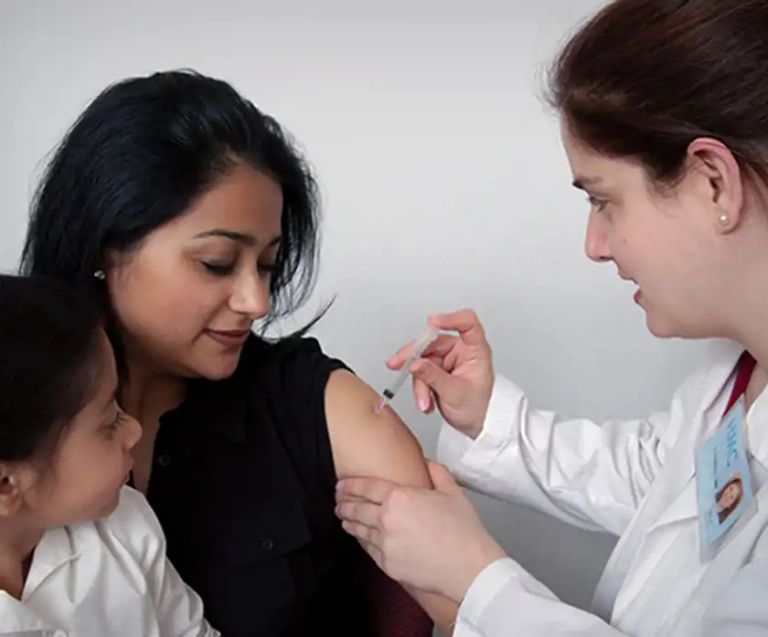 Kvinna med barn blir vaccinerad av en kvinnlig läkare.