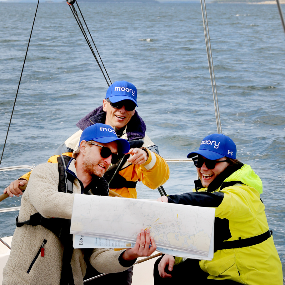 De tre grundarna av Moory på en segelbåt läser ett fysiskt sjökort. 
