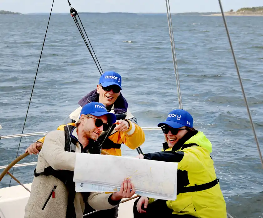 Christoffer Tyrefors, Torkel Hallander och Gustav Gavenas läser sjökort på en segelbåt.