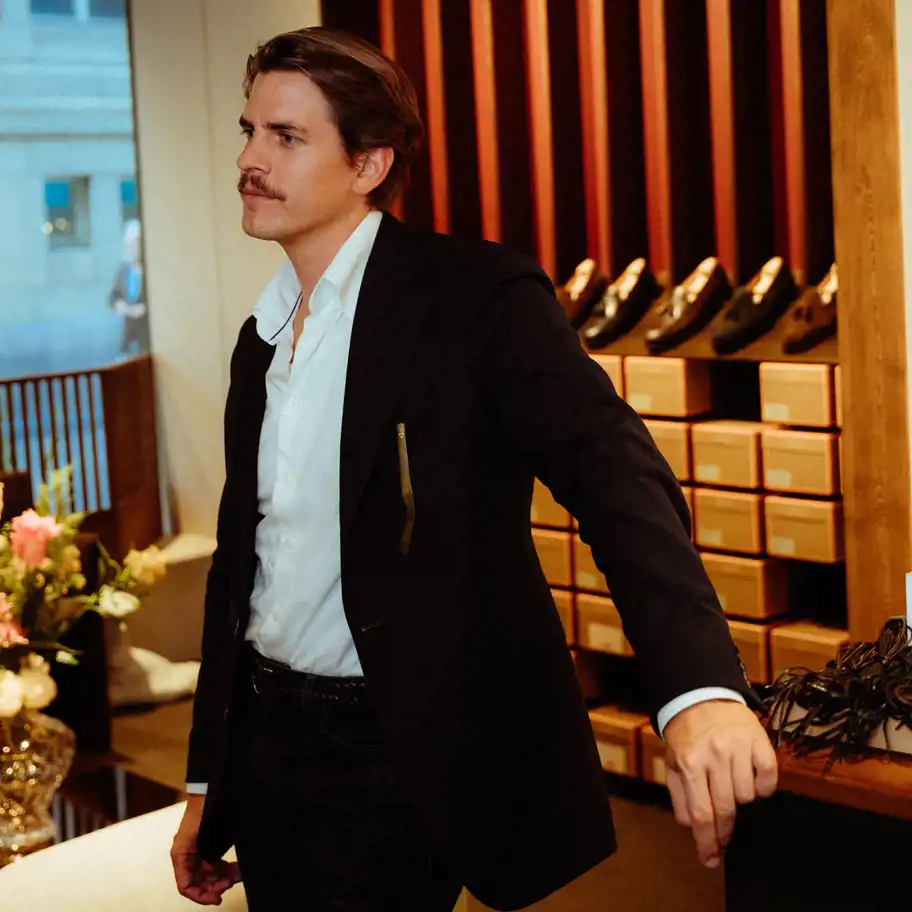 Sebastian Öhrn, vd och grundare av Myrqvist, står i butikens showroom med eleganta skor uppställda på hyllan bakom sig.