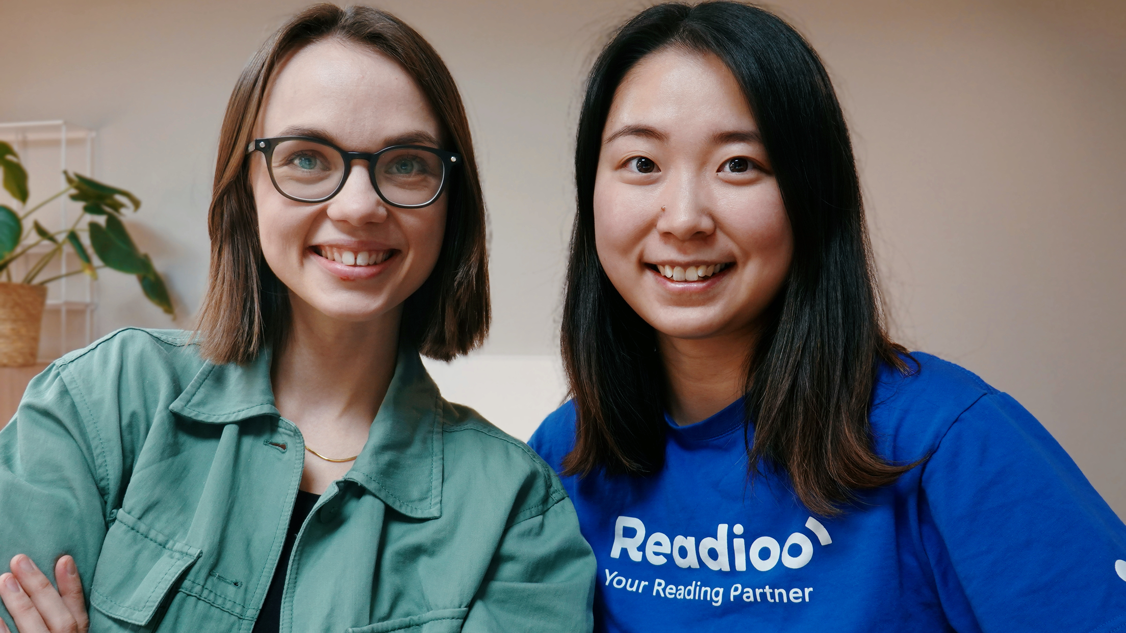 Linda Wennerström och Inga Li, två av grundarna till Readioo, står bredvid varandra och ler mot kameran. Inga bär en blå tröja med Readioo-logotypen.