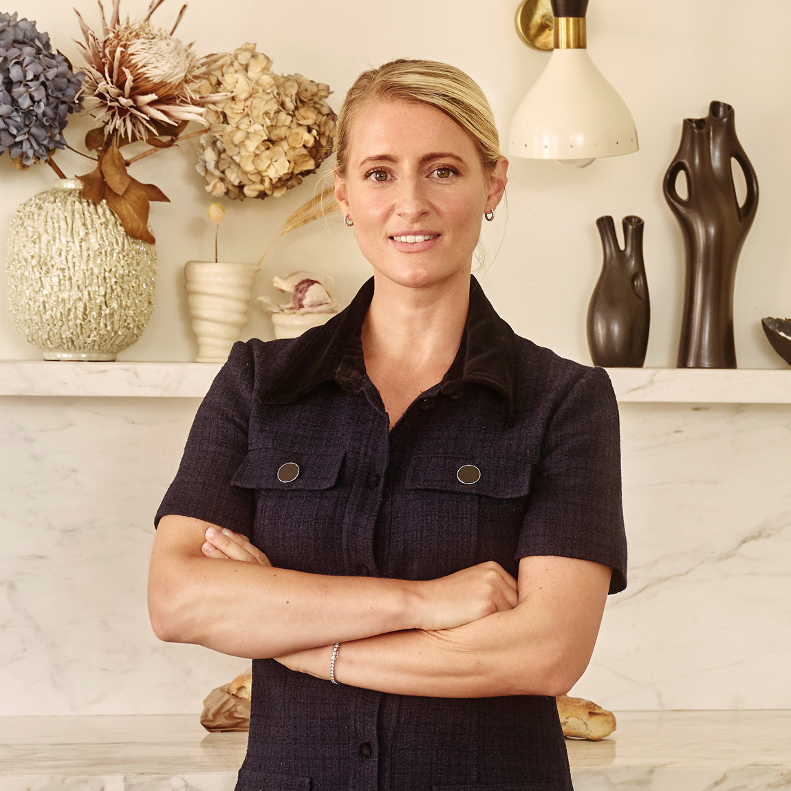 En av grundarna till Sigrid Therapeutics står inomhus med armarna i kors framför en hylla med keramik och torkade blommor.