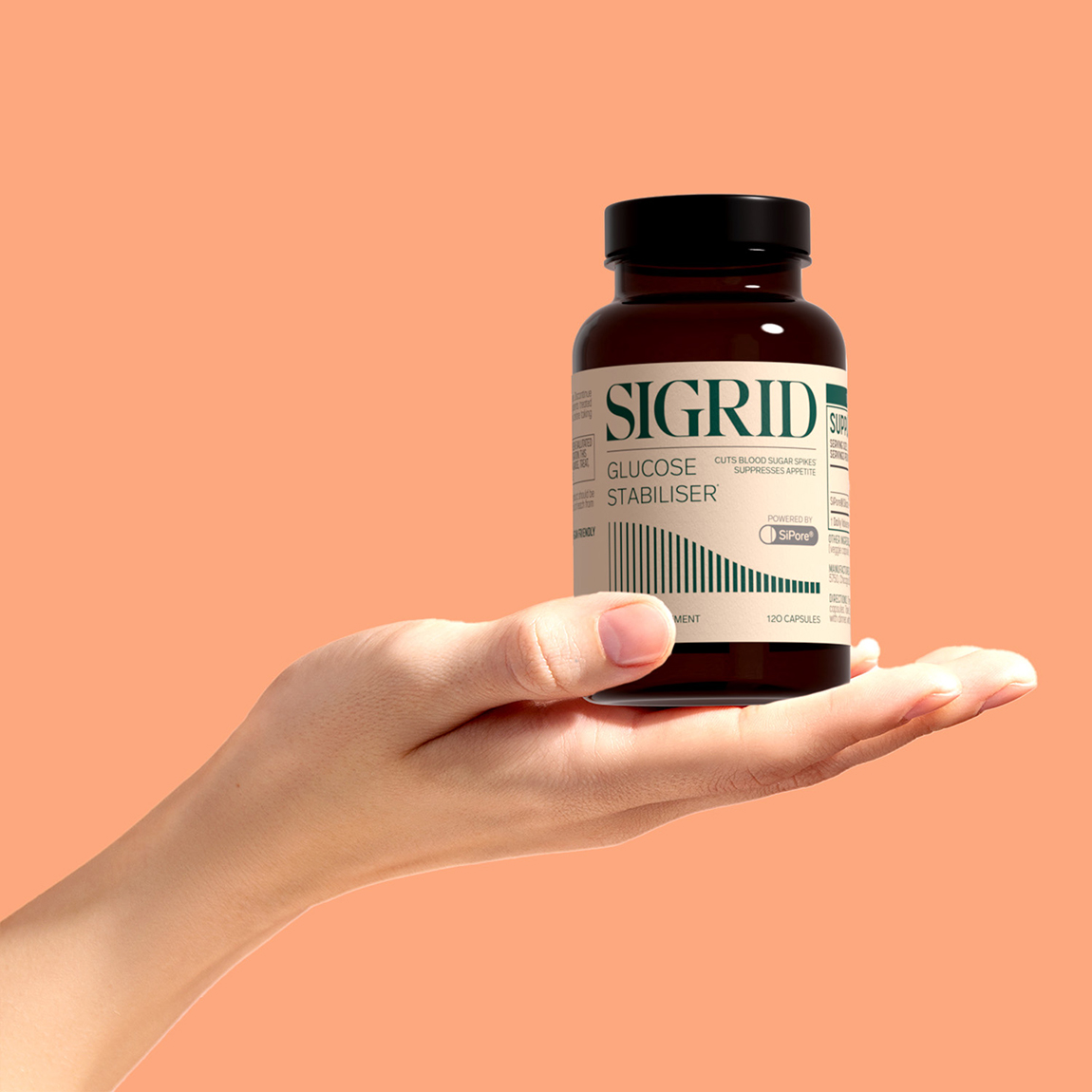 En hand håller upp en burk med kosttillskottet Sigrid Glucose Stabiliser från Sigrid Therapeutics mot en enfärgad persikofärgad bakgrund.