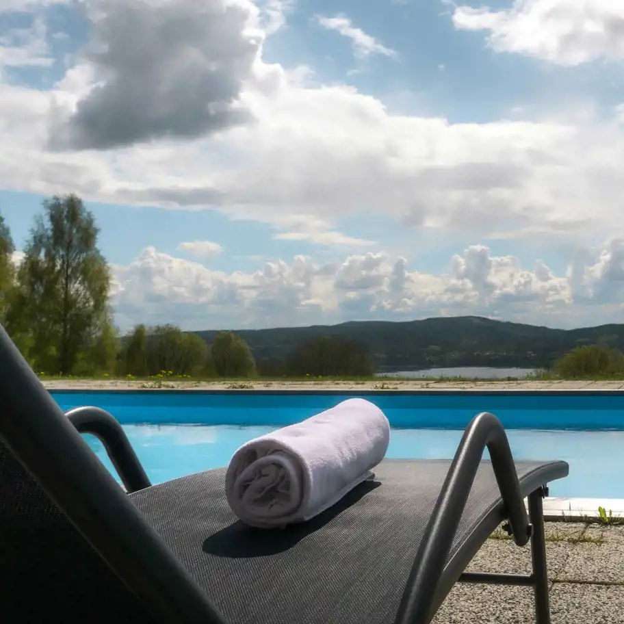 En solstol i i förgrunden framför en pool och berg i bakgrunden.