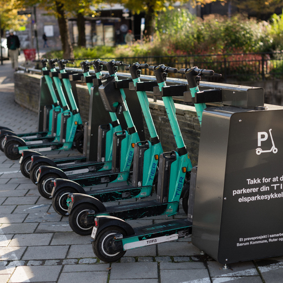 En rad elsparkcyklar från företaget TIER står parkerade vid en särskilt anvisad station på en stadsgata. Bilden illustrerar hållbara och moderna transportlösningar – en typ av innovation som kan utvecklas vidare med hjälp av Almis finansiering som till exempel grönt lån.