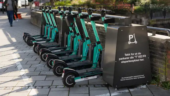 En rad elsparkcyklar från företaget TIER står parkerade vid en särskilt anvisad station på en stadsgata. Bilden illustrerar hållbara och moderna transportlösningar – en typ av innovation som kan utvecklas vidare med hjälp av Almis finansiering som till exempel grönt lån.