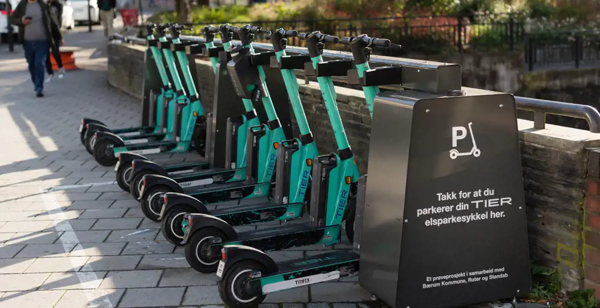 En rad elsparkcyklar från företaget TIER står parkerade vid en särskilt anvisad station på en stadsgata. Bilden illustrerar hållbara och moderna transportlösningar – en typ av innovation som kan utvecklas vidare med hjälp av Almis finansiering som till exempel grönt lån.