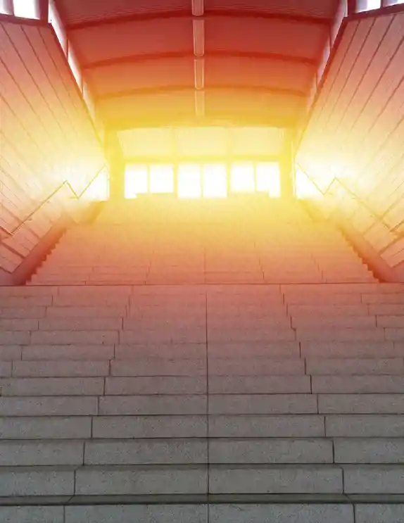 En trappa som leder upp till en solupplyst utgång.  