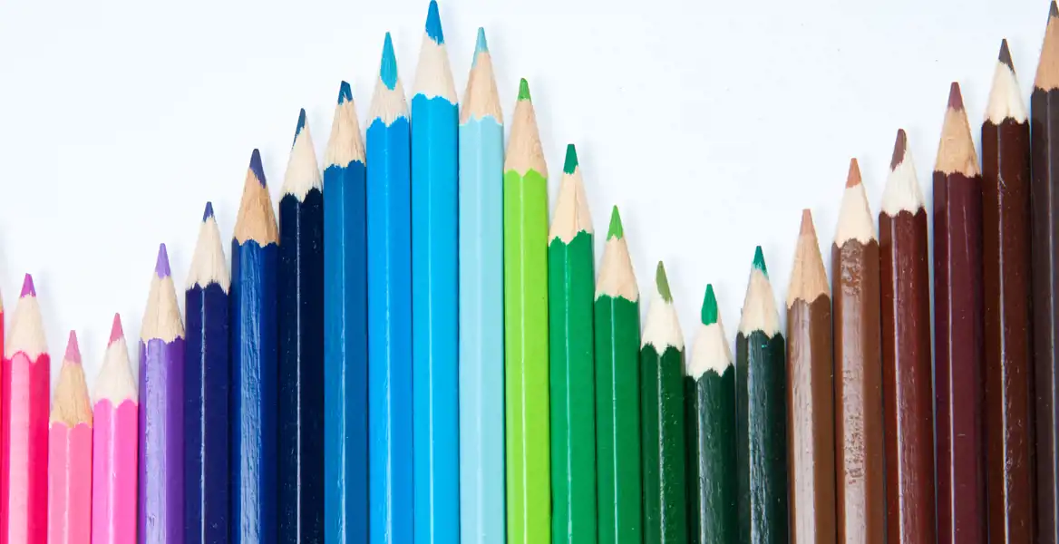 Flera blyertspennor i olika färger som bildar en våg. 