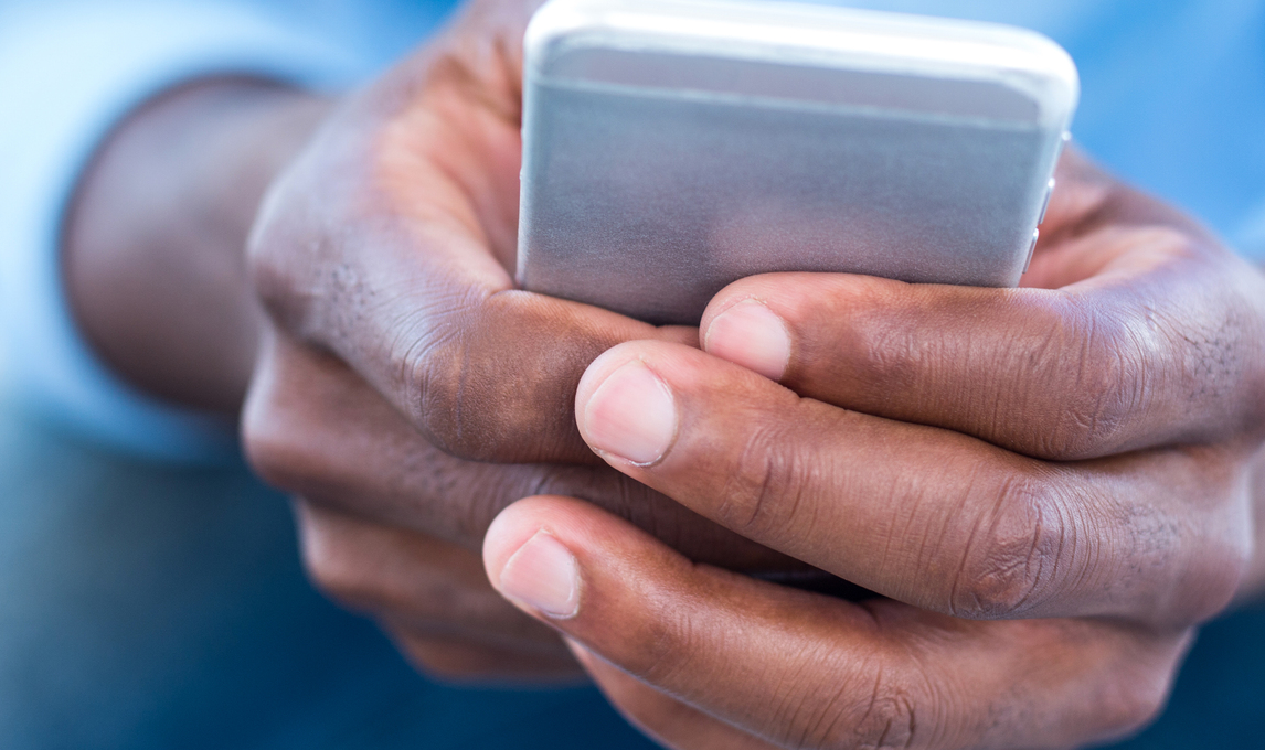 Närbild på två händer som håller i en smartphone. Personen använder telefonen, vilket antyder mobil kommunikation eller digital interaktion.