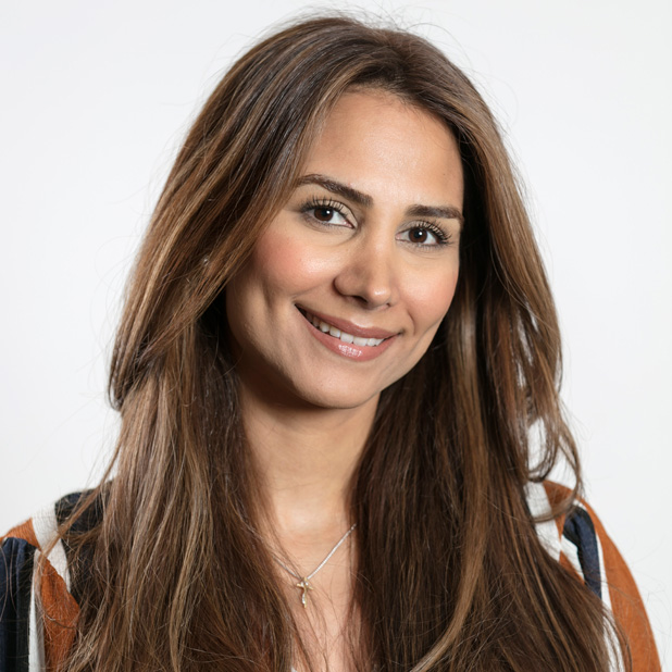 Kvinna med långt brunt hår, ler varmt och ser in i kameran mot en ljus bakgrund. Maggie Malek är rådgivare på Almi.