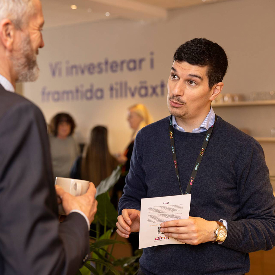 Två personer som samtalar. I bakgrunden syns texten Vi investerar i framtida tillväxt.