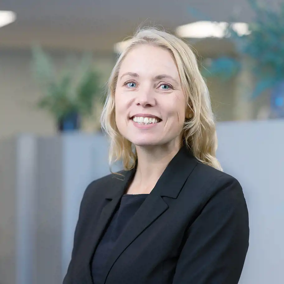 kvinna med halvlångt ljust hår ler mot dig