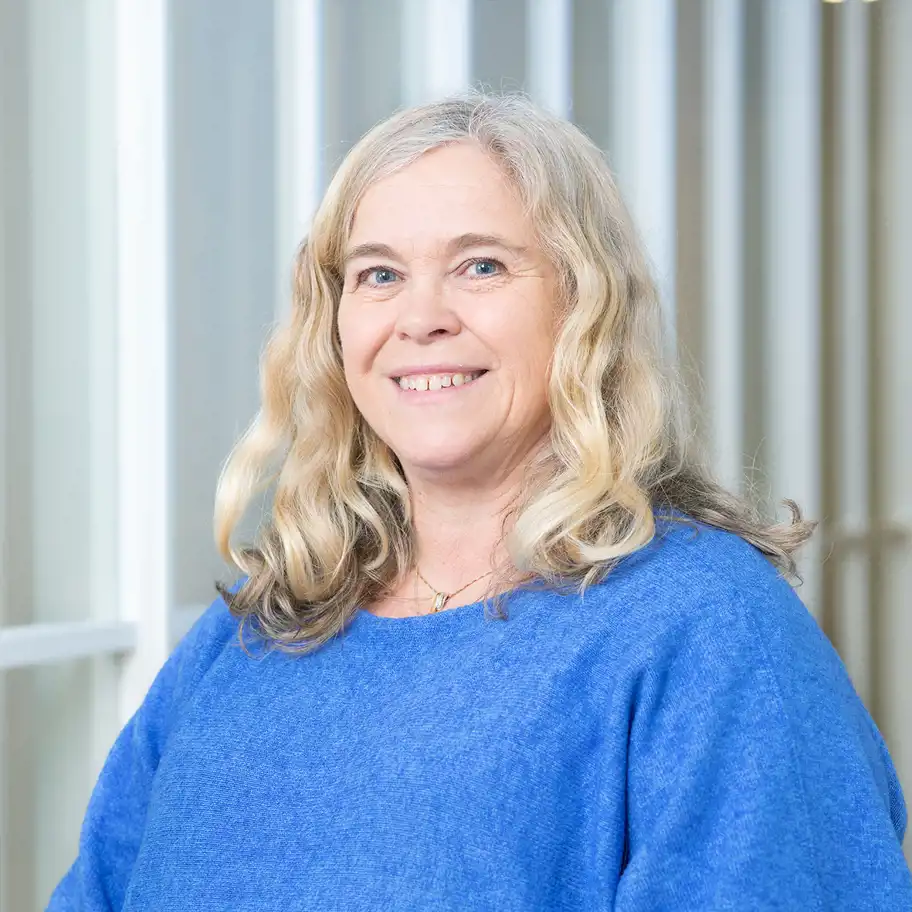 kvinna med ljust lockigt hår ler mot kameran