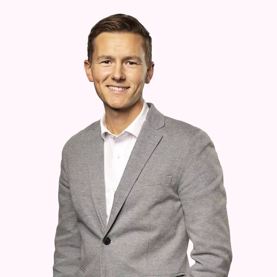 Adam Widebert, Investment Manager at Almi Invest, smiling in a grey blazer and white shirt against a light pink background.