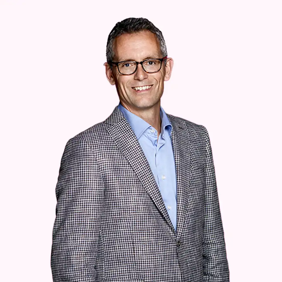 Alex Molvin, Fund Manager at Almi Invest South, smiling in a checked blazer and blue shirt against a light pink background.