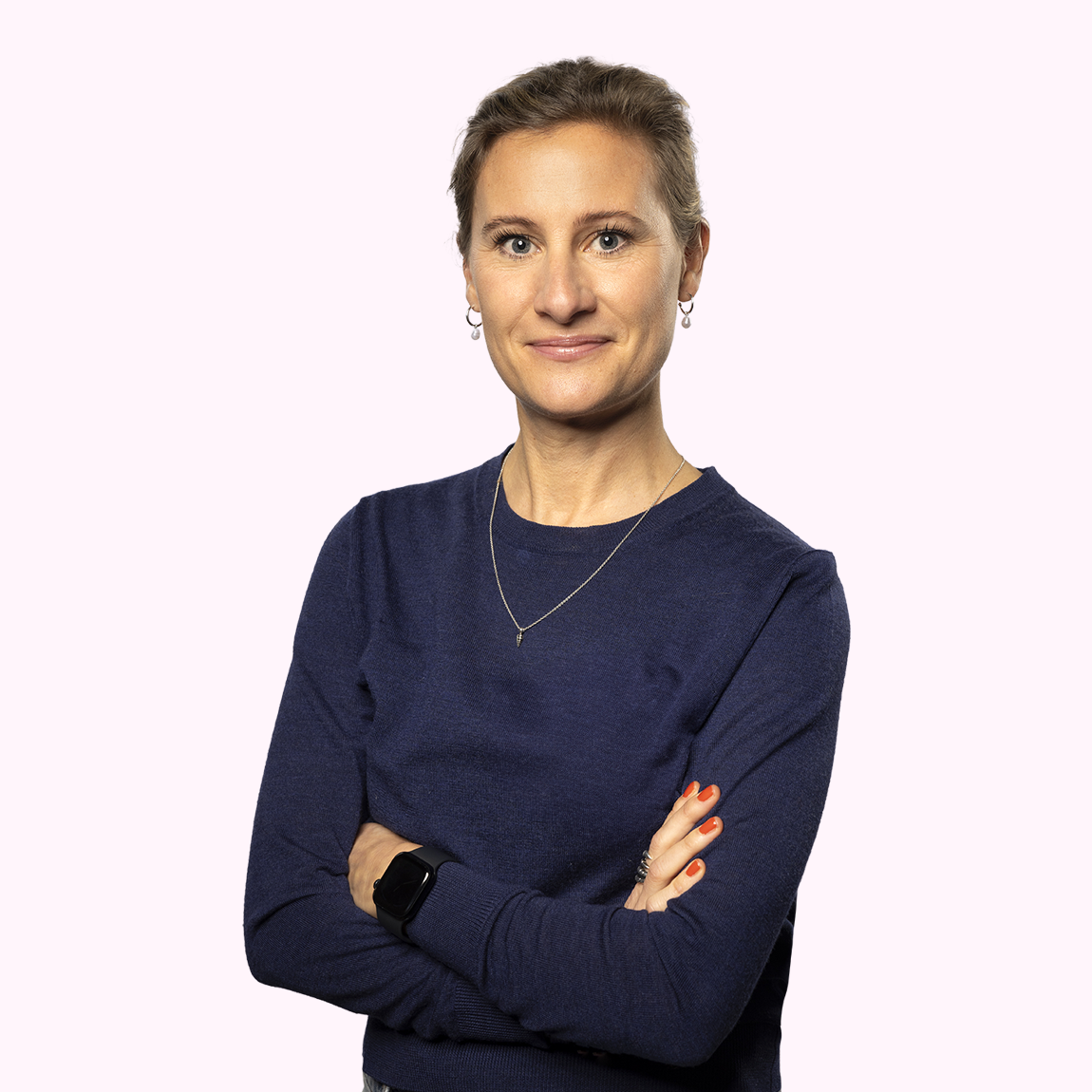 Anna Wennerstein, Marketing Manager på Almi Invest, står med armarna i kors med ett leende, klädd i mörkblå tröja mot en ljusrosa bakgrund.