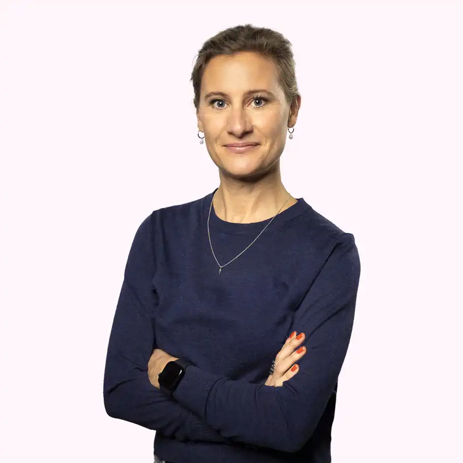 Anna Wennerstein, Marketing Manager at Almi Invest, smiling with arms crossed, wearing a dark blue sweater against a light pink background.