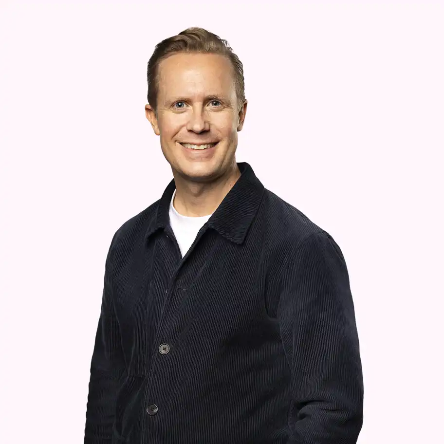 Jonas Bergqvist, Investment Manager at Almi Invest GreenTech, smiling in a dark corduroy jacket and white T-shirt against a light pink background.