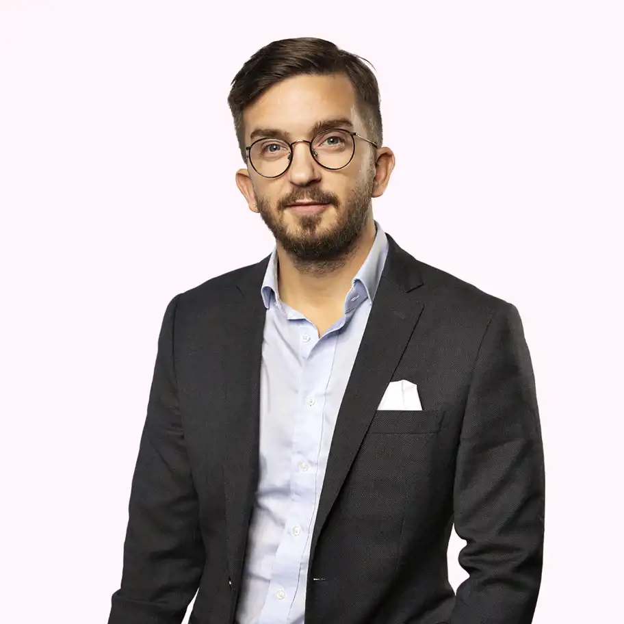 Jonathan Lannö, Investment Manager på Almi Invest GreenTech, står i mörk kostym med ljusblå skjorta och vit näsduk, mot en ljusrosa bakgrund.