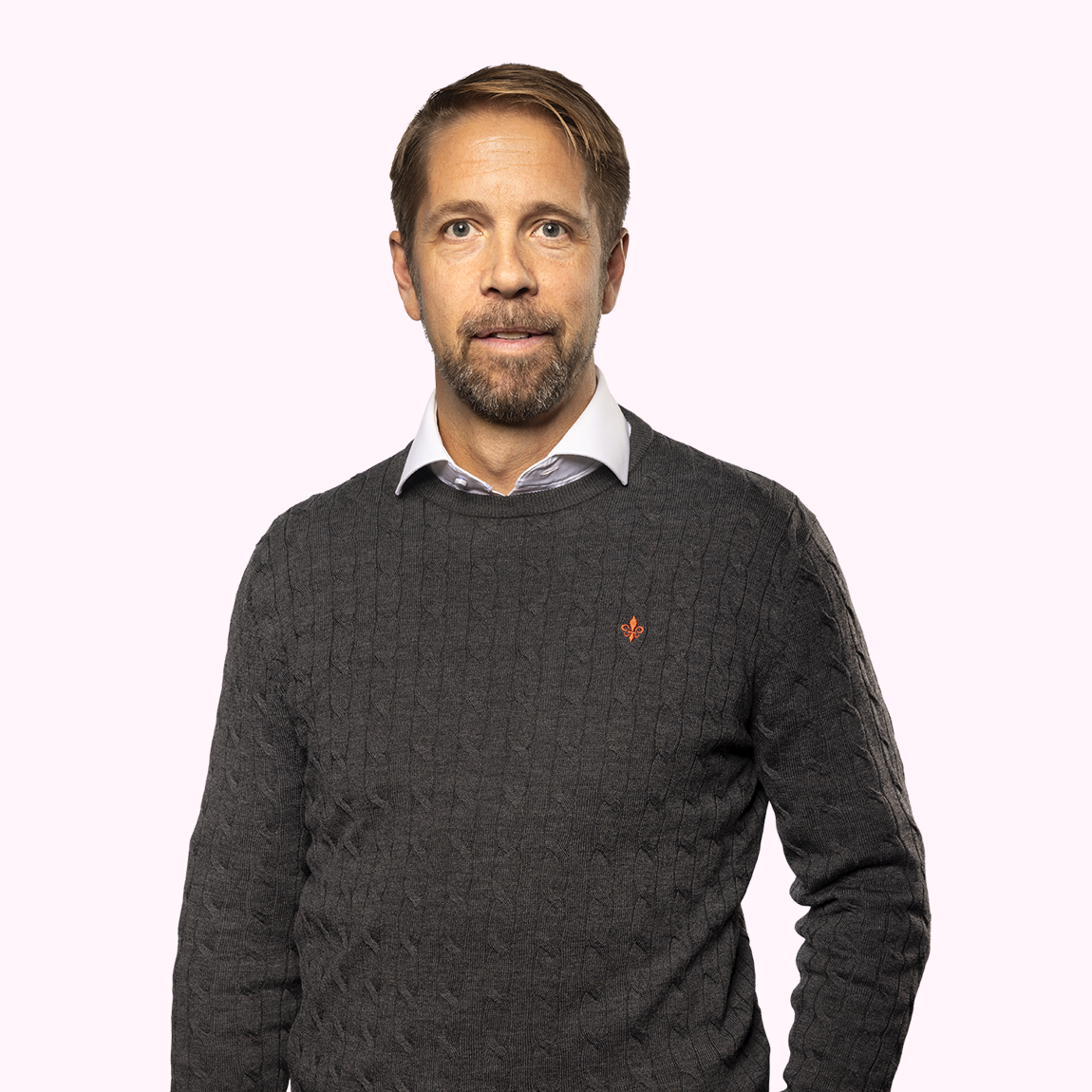Jörgen Bodin, Fund Manager på Almi Invest GreenTech, står i mörk kabelstickad tröja och vit skjorta mot en ljusrosa bakgrund.