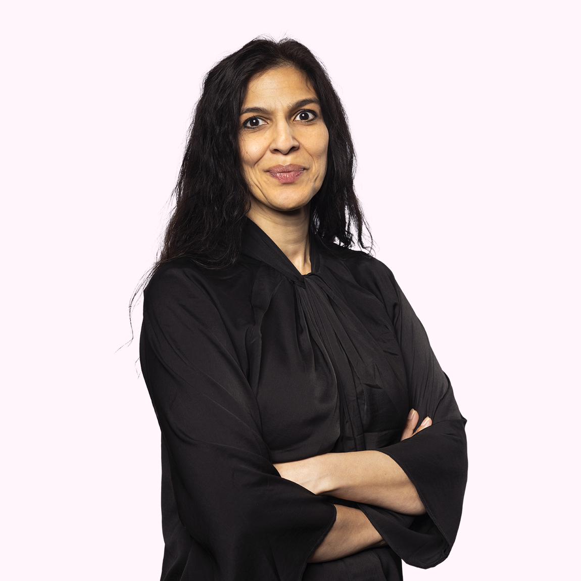 Kavita Björkdahl, Finance Manager på Almi Invest, står med armarna i kors och ett lugnt leende, klädd i svart blus mot en ljusrosa bakgrund.