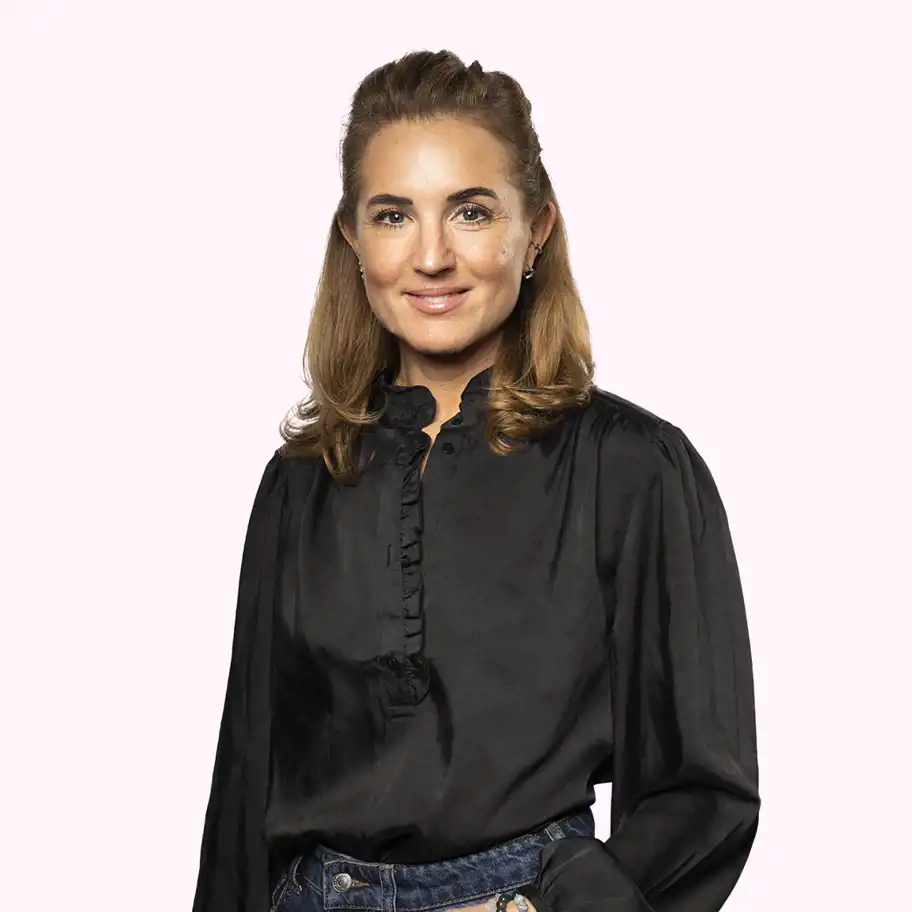 Linda Murray Wennberg, Investment Manager at Almi Invest GreenTech, smiling in a black blouse and blue jeans against a light pink background.