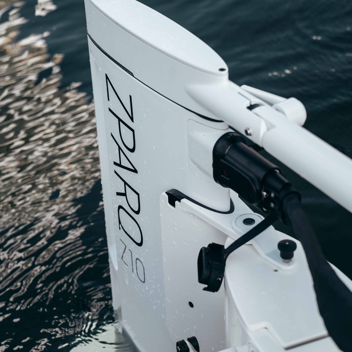 Närbild på en vit elektrisk utombordsmotor från Zpark, modell Z10, monterad på en båt i vattnet. Vattendroppar syns på motorn.