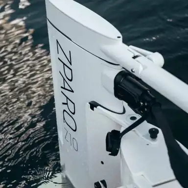 Närbild på en vit elektrisk utombordsmotor från Zpark, modell Z10, monterad på en båt i vattnet. Vattendroppar syns på motorn.
